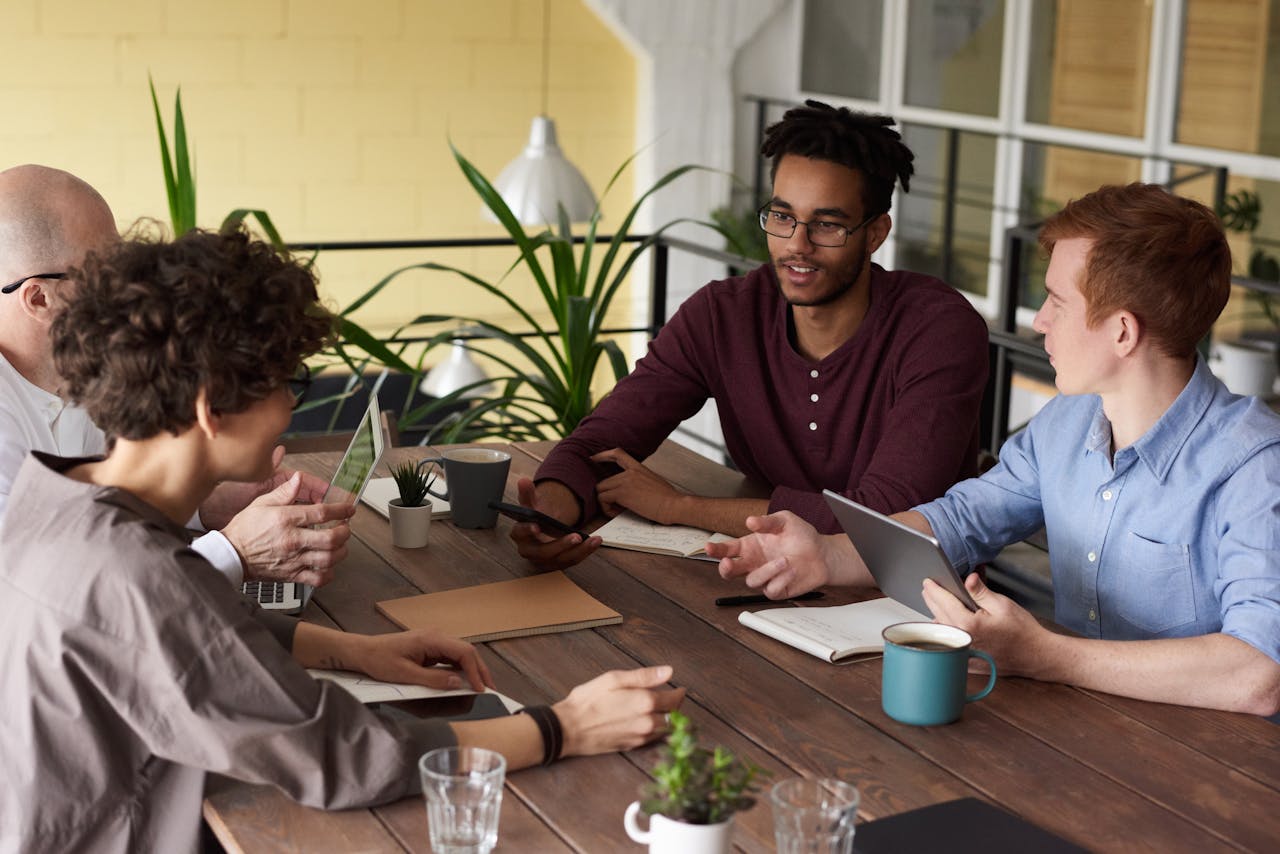 A diverse group of colleagues brainstorming at a wooden table in a modern indoor office setting.