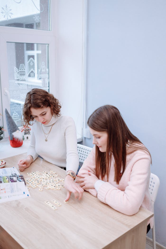 Two women enjoying a board game together in a cozy indoor environment, focusing on the game.
