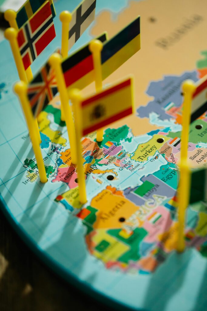 Close-up of a world map with various country flags on pin poles highlighting Europe.