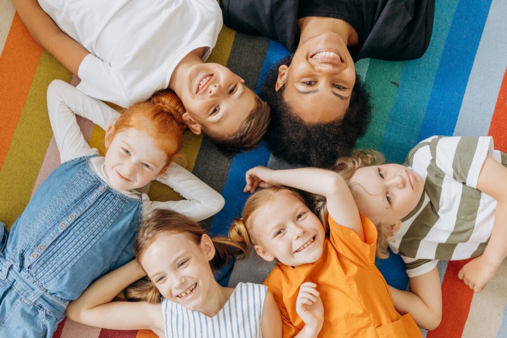 Happy group of children smiling while lying on a colorful rug, showcasing friendship and joy.